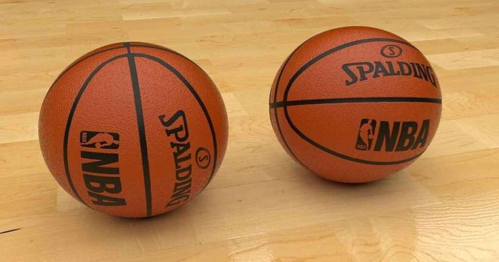 Two Spalding NBA basketballs sit on a wooden court floor, perfectly spaced at 40 inches apart.